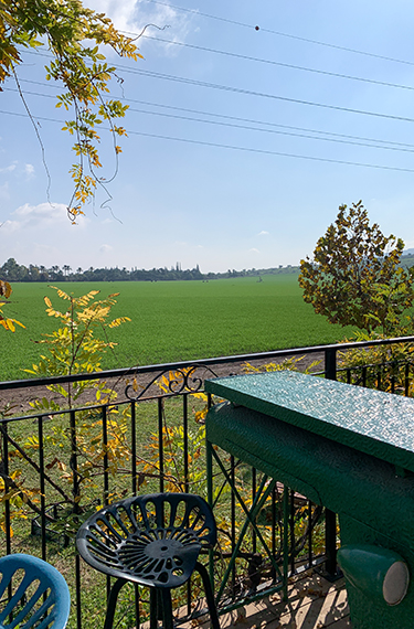 כסא ושולחן מברזל צבעוני במרפסת היפה הפונה לשדות. מסעדת ארטישוק ליד בית אלפא