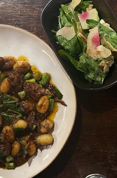 ניוקי עם בשר מפורק שבושל בישול ארוך ולצידו סלט ירוק בסומסומיה במצפה רמון